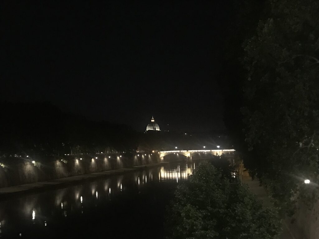 Night view of the dome of St. Peter's Basilica from across the River Tiber